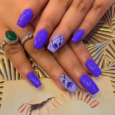 A beautiful set of square nails in a vibrant purple. The ring fingers are accented with a lighter lavender base and delicate, hand-painted purple flowers.