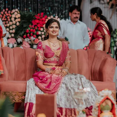 A client looking beautiful at her event in a custom Langa Dhawani, featuring a grey and maroon skirt paired with a pink embroidered blouse.