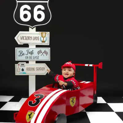 Ready, set, go! This little racer is all smiles in our custom Route 66 setup, complete with a Ferrari-inspired car and checkered floor. It's a high-energy theme perfect for an adventurous toddler.