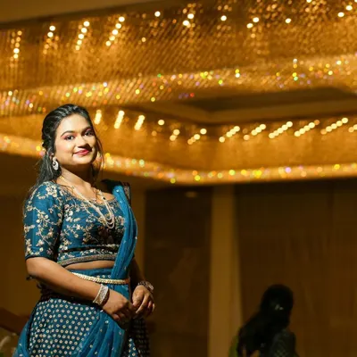 A stunning reception look under dramatic lighting. The bride wears an embroidered blue lehenga, and her makeup features a defined eye and a warm lip color, creating a chic and polished style.