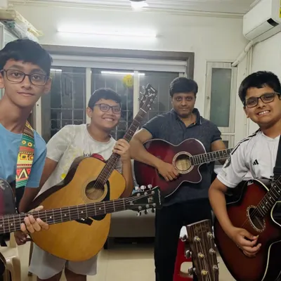 There's nothing like the energy of a group guitar class. Here, our students and a coach share a moment of camaraderie after a productive session, each holding their instrument with pride.