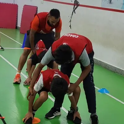 Our coaches are always on hand to provide personalized feedback and adjustments. Here, a coach helps a young athlete perfect their form during a drill, ensuring they perform the movement correctly and safely.