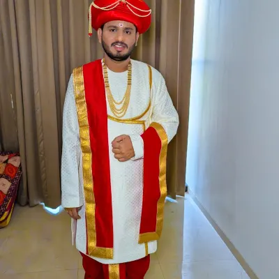 A classic Maharashtrian groom in a Peshwai look. The red turban, simple white kurta, and traditional jewelry create a timeless and regal appearance for the wedding vidhi.