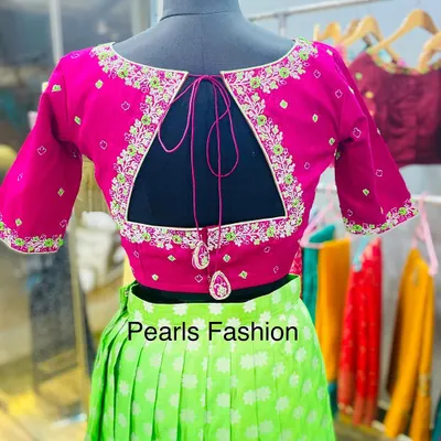 A bright pink blouse with a triangular keyhole back design. The cutout is framed with neat floral embroidery, and the tie-up has matching fabric latkans.