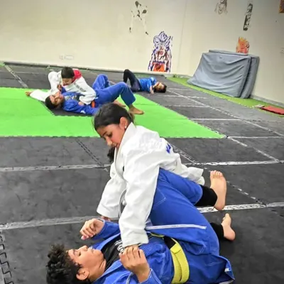 This is where technique beats strength. In our Jiu-Jitsu classes, kids learn how to control an opponent on the ground. This student is practicing a dominant position, learning to stay calm and apply pressure correctly.