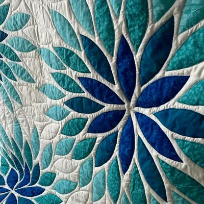 A close-up of the "Sea Glass" quilt, where the leaf-shaped quilting pattern flows beautifully around the curved appliqué pieces, adding a sense of movement.