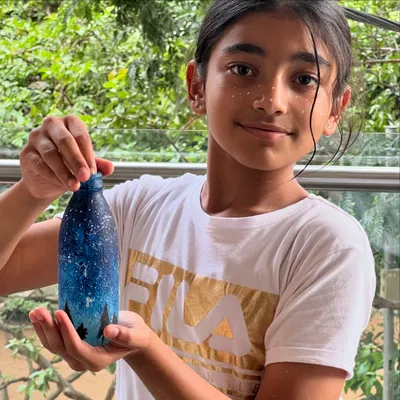 Why stop at the bottle? This young artist created a beautiful night sky on this bottle and couldn't resist adding a few starry freckles to her face too! This is what pure, creative fun looks like.