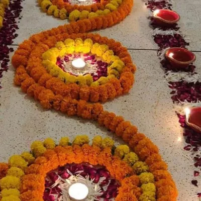 This is a floral rangoli I made using marigold strings to create spiral patterns. I placed diyas in the center of each spiral and scattered rose petals to complete this traditional floor decoration.