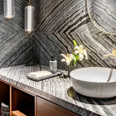 A closer look at the dramatic book-matched granite in the Parishram residence powder room. The dynamic veining of the stone is complemented by minimalist pendant lights and a simple vessel sink.
