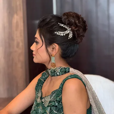 A chic and messy high bun, perfect for a reception or cocktail party. The delicate silver accessory adds a touch of modern elegance.