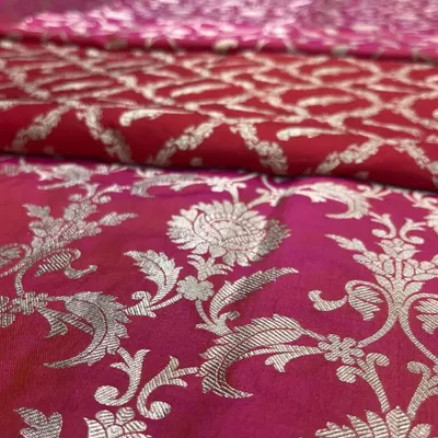 The heart of Banarasi weaving. This close-up reveals the dense, silver zari work on a rich magenta silk fabric, a hallmark of the luxurious bridal sarees we are known for.