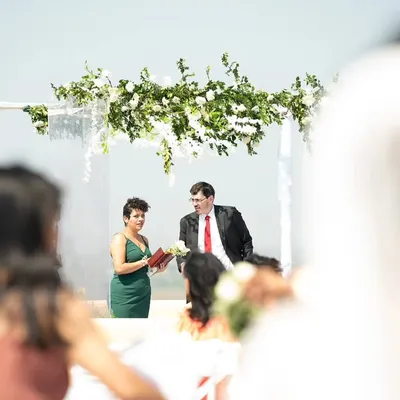 The moment she says "I do." This shot captures the Christian wedding ceremony from the bride's perspective, focusing on the groom and the officiant under a beautiful floral arch.