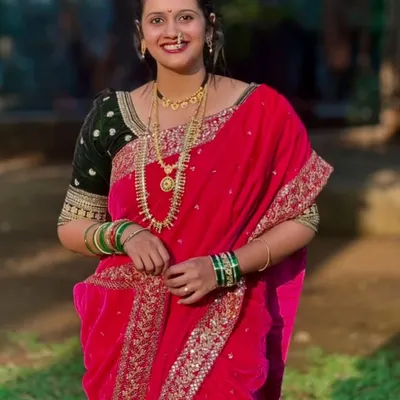 A beautiful close-up of a client wearing the pink velvet Nauvari saree, complete with traditional jewelry like the nath and layered necklaces. Her smile says it all.