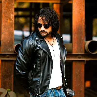 The classic leather jacket and jeans combo gets an extra edge from the industrial backdrop of rusted beams and pipes.