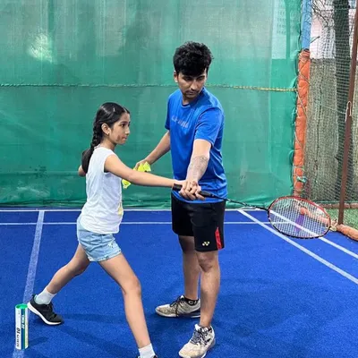 Perfecting the grip is the first step to a powerful game. Our coach provides hands on instruction to a young student, ensuring she learns the correct badminton grip technique for better control and shot accuracy.