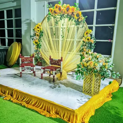 A classic Haldi ceremony stage. This setup features a circular backdrop with yellow drapes and is decorated with bright sunflower arrangements to match the traditional yellow theme.