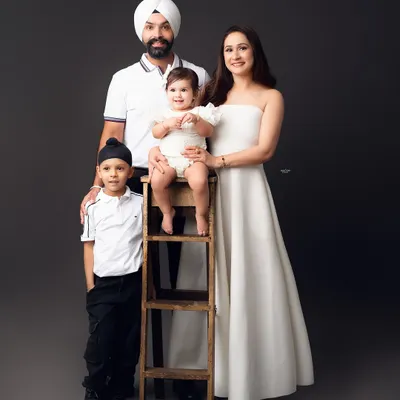 A picture of modern elegance. This family's coordinated black and white outfits create a sharp, stylish look against the dark grey backdrop, resulting in a sophisticated family portrait.