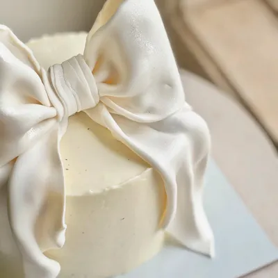 A close-up of the hand-sculpted fondant bow, showing the realistic fabric-like folds and texture. This detail is what gives the cake its couture feel.