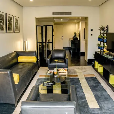 Welcome to our Premier Suite, where sophistication is in every detail. The spacious living area features plush leather sofas and curated art, creating an ideal setting for both relaxation and entertaining.
