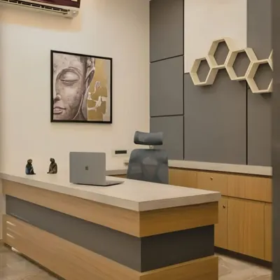 This private office design balances professionalism with personal taste. It features a two-tone desk, an ergonomic chair for comfort, and unique wall decor including honeycomb shelving and serene artwork to create a calm and focused workspace.