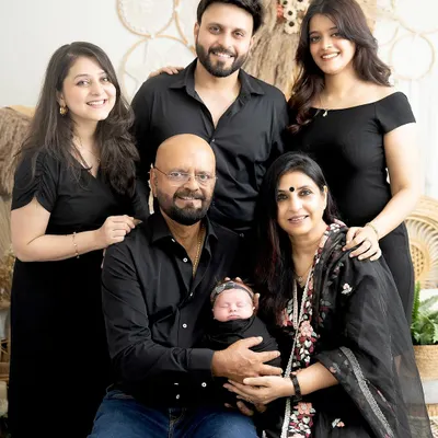 A beautiful multi-generational family portrait. The grandparents hold their newborn grandchild, surrounded by the love of their children and other grandchildren. This is a true family heirloom.