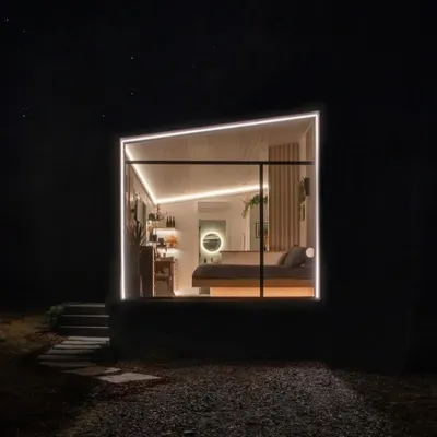 A beautifully lit modular living space at night. The combination of large windows and strategic LED lighting creates a warm, inviting ambiance, showcasing the home's modern design.