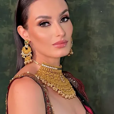 This is a classic bridal look created for a jewelry campaign. The makeup is defined and elegant, with a sharp winged liner and warm tones to complement the heavy gold jewelry and traditional red and green lehenga.