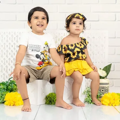 A charming portrait of a brother and sister sitting together. Their coordinated yellow and black outfits are stylish and fun for a kids' photoshoot.