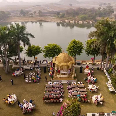 An aerial view of a breathtaking lakeside wedding ceremony at Shikarbadi Hotel, Udaipur. I designed this golden-domed mandap to be the focal point, perfectly positioned to capture the serene beauty of the natural landscape.