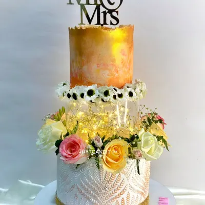 A beautiful wedding cake with a modern twist. I used a cake spacer with fairy lights to create a magical floating effect between the tiers, complemented by fresh flowers.