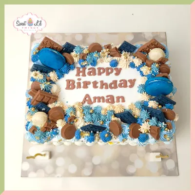 A chocolate lover's dream! This rectangular cake is loaded with blue and white piped frosting, chocolate pieces, and macarons, perfect for Aman's birthday.