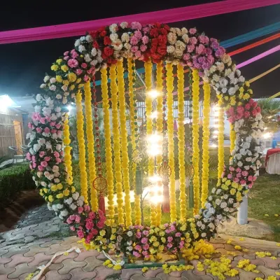 A circular floral frame is a popular choice for outdoor Haldi and Mehendi events. Here, I created a large ring with colorful flowers and hanging marigold strings, which looks fantastic in night-time photos.