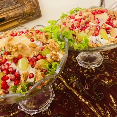 Two large bowls of my super delicious and refreshing Russian Salad. They are generously topped with walnuts, pomegranate seeds, and grapes over a bed of lettuce.