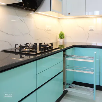 A close-up of our high-gloss turquoise kitchen, featuring a convenient pull-out spice rack next to the hob. The design is complemented by a black granite countertop and a white marble-look backsplash.