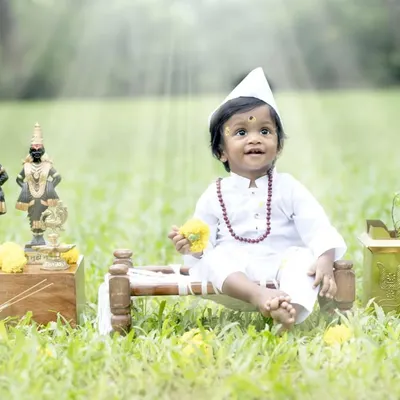 Jai Hari Vitthala. This little boy is dressed as a tiny Varkari, complete with a topi and tulsi plant, in a divine outdoor setting.