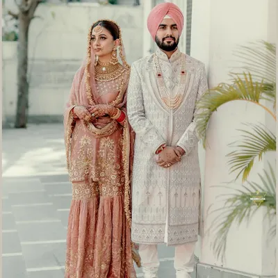 A classic portrait of a Sikh couple after their Anand Karaj. Their coordinated pastel outfits and the elegant setting create a picture of grace and tradition.