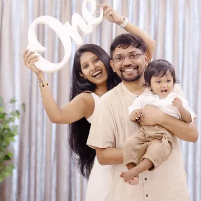 Celebrating turning one with a fun family photo. Using props like this 'One' sign adds a special touch to first birthday milestone sessions in the studio.