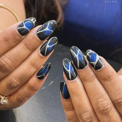 A bold and graphic design for a modern look. We combined a deep blue cat-eye effect with sharp, silver geometric lines over a black base to create this striking and futuristic nail art.