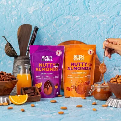 A product-focused shot for Open Secret's Nutty Almonds, showcasing two flavor varieties in one frame. This composition is great for website banners or ads comparing different product offerings.