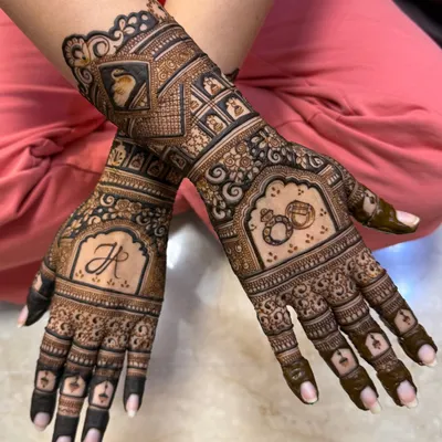 An elegant engagement mehendi featuring the couple's initial, intertwined rings, and a portrait of the bride. It's a beautiful way to celebrate the start of a new journey.