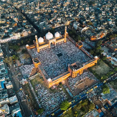 This wide aerial shot of Jama Masjid shows the historic mosque surrounded by the dense cityscape of Old Delhi during Eid. It captures the context of the gathering, showing how faith is woven into the fabric of the city.
