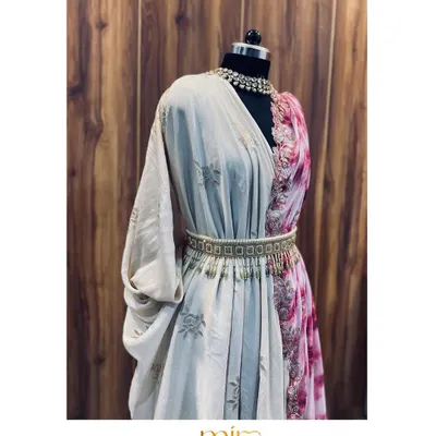 A custom pre-draped saree in a soft beige, contrasted with a splash of pink tie-dye. The look is brought together with an embellished belt, offering the elegance of a saree with modern convenience.