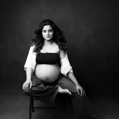 A powerful and intimate black and white maternity portrait. This image focuses on the beautiful shape of her baby bump and her serene expression, creating a timeless piece of art.
