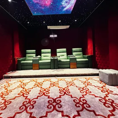A full view of a private cinema we designed, showcasing the custom patterned carpet, elevated platform for optimal viewing angles, and the stunning galaxy-effect ceiling. Every element is chosen to enhance the cinematic feel.