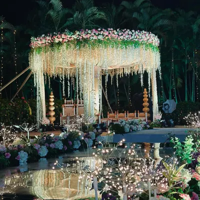 Our signature poolside mandap, where floral elegance meets serene water reflections. The hanging floral strings and fairy lights create an absolutely blissful and romantic atmosphere for an evening ceremony.