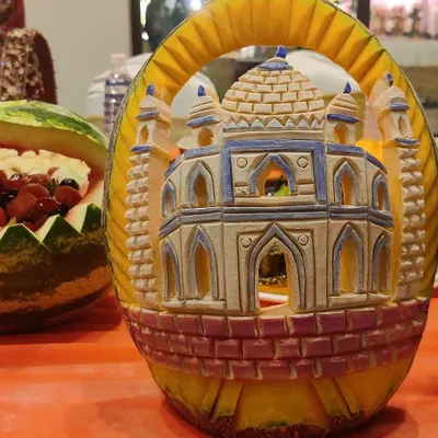 A testament to our presentation skills. This is an intricate carving of a monument, likely the Taj Mahal, made from a pumpkin. It’s a stunning centerpiece that showcases our attention to detail.