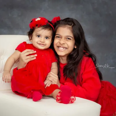 The bond between siblings is so special. This studio portrait of two sisters, coordinated in bright red, showcases that sweet and happy connection that I love to photograph.