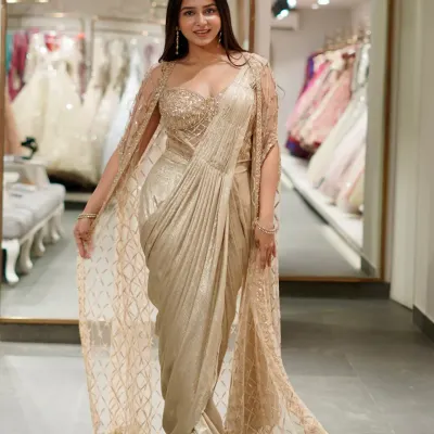 A saree that shines brighter than jewels. This golden pre-draped saree with a matching embellished cape is pure luxury and glamour.