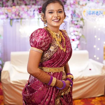 A smiling bride in a magenta Peshwai Nauvari saree. The puffed sleeves on the blouse are a classic detail for this traditional bridal outfit.