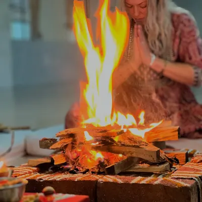 A participant offers prayers with folded hands before the sacred fire of the homam. The intensity of the flame symbolizes the burning away of impurities and the awakening of inner light.